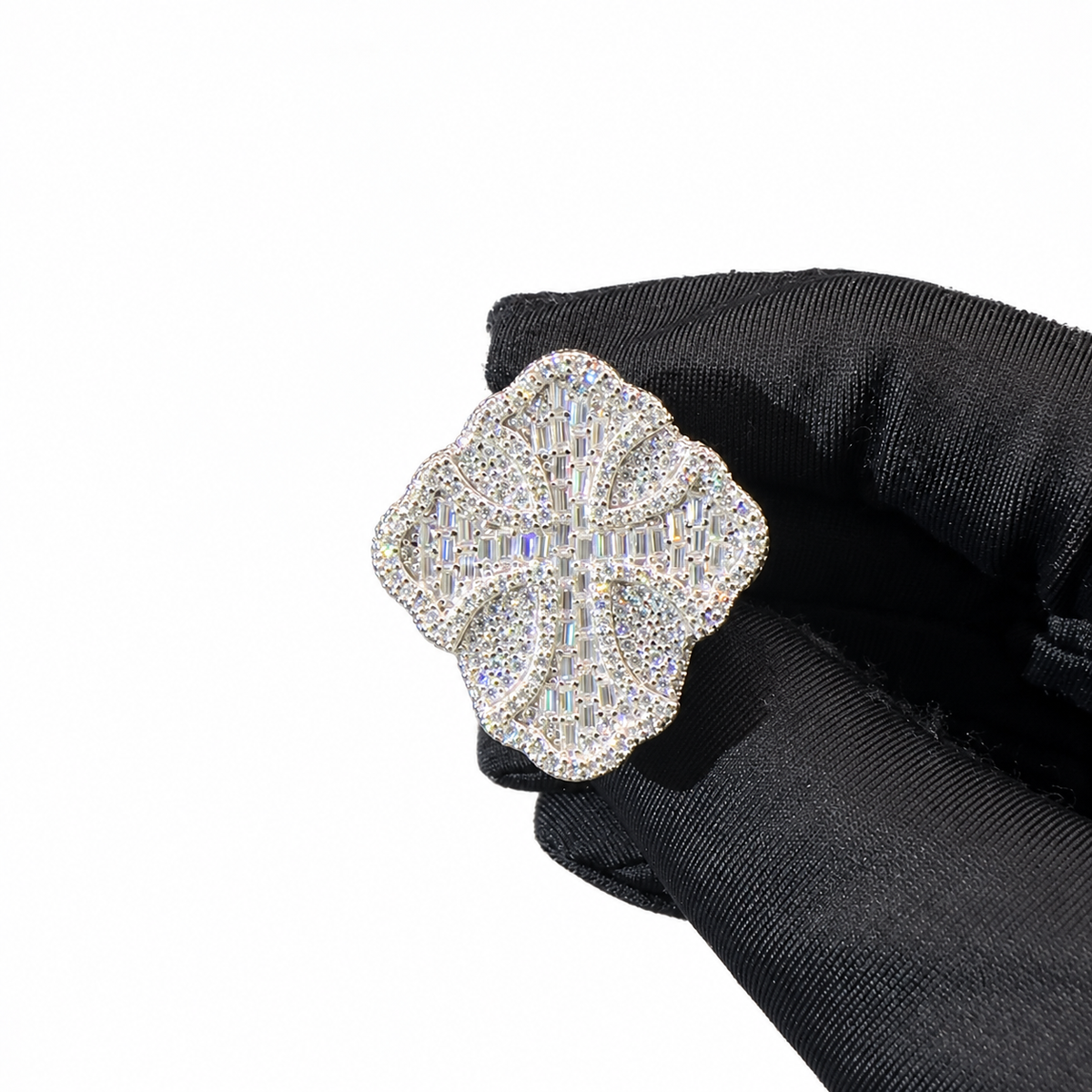 A close-up of a silver-toned flower-shaped ring paved with clear crystals, held by a black gloved hand against a plain white background.