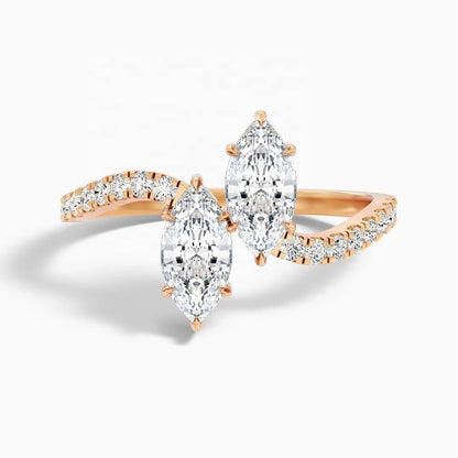 Rose gold ring with three marquise-cut diamonds and smaller accent diamonds along curved shanks, shown on a clean white background.